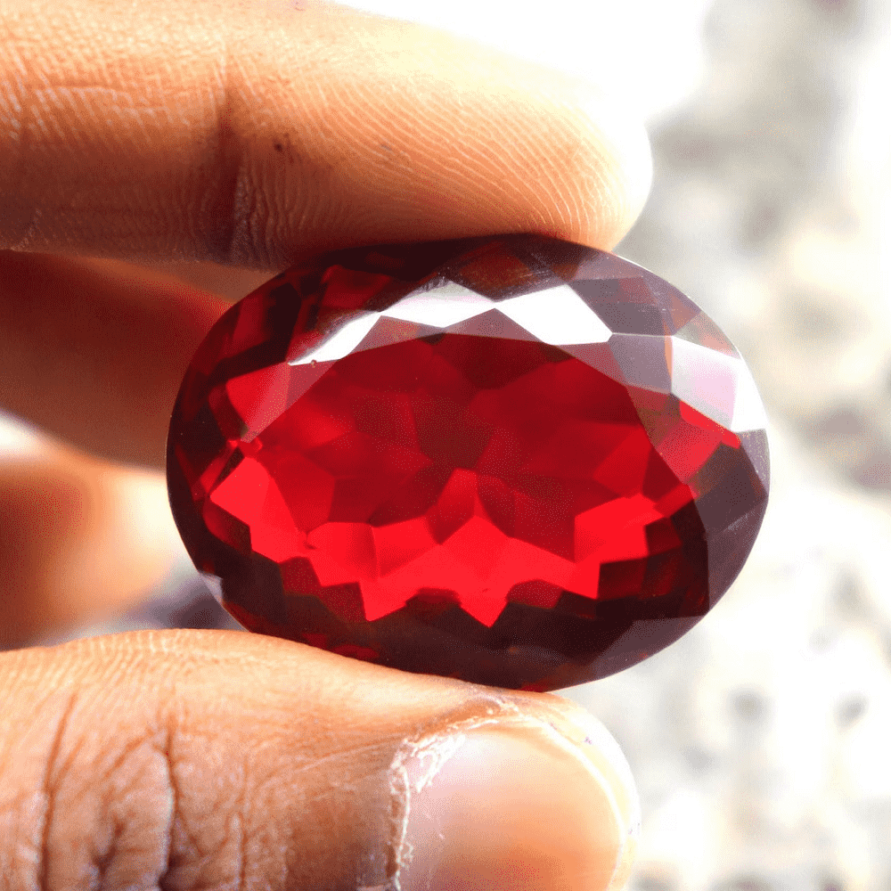 Handheld polished Ruby Stone with a deep red color and faceted surface for jewelry making