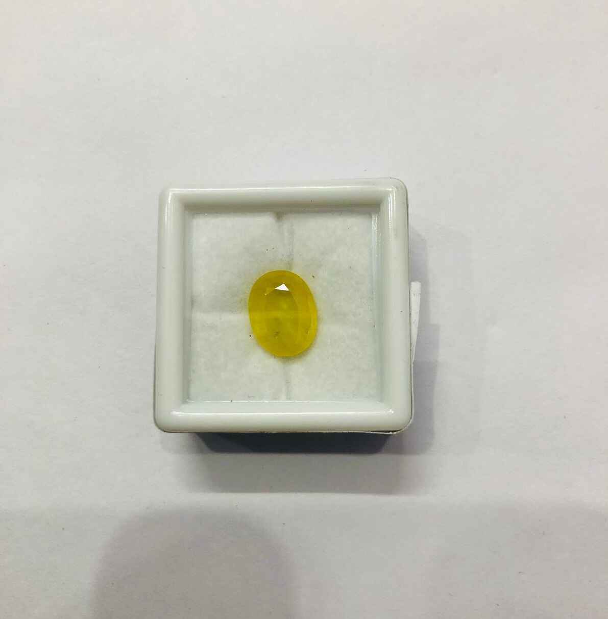 Natural Yellow Sapphire Stone in a display box, featuring a vibrant yellow hue and smooth surface