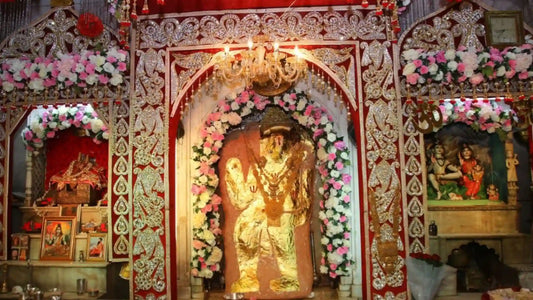 Decorated temple altar featuring a golden idol surrounded by flowers for Shri Pretraj Chalisa worship