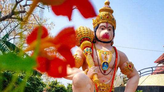 Statue of Lord Hanuman Surrounded by Flowers with Shri Balaji Aarti in the Background