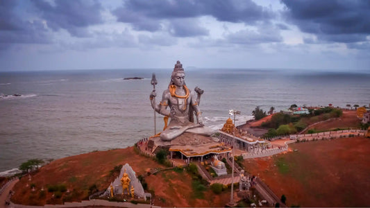Aerial view of a large statue of Lord Shiva overlooking the sea, representing Shri Vishvanath Ashtakam