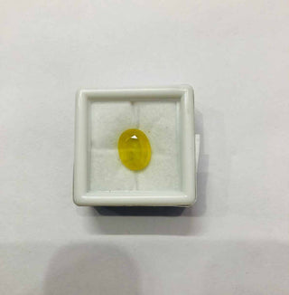 Natural Yellow Sapphire Stone in a display box, featuring a vibrant yellow hue and smooth surface